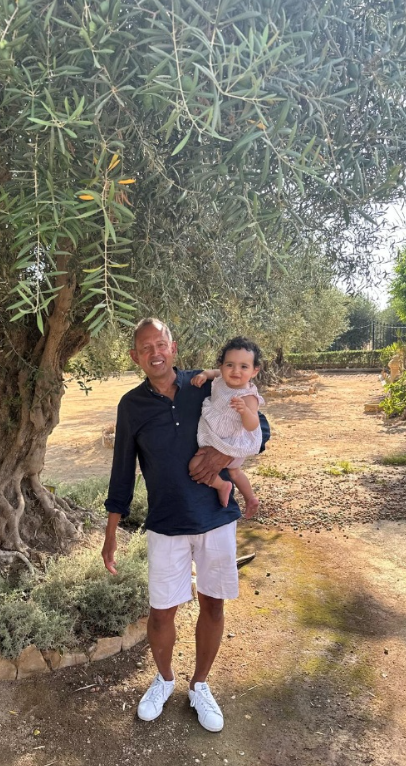 Eduardo Cervera with his grandchild among the family olive trees in Cascante